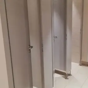 Mehrere geschlossene und teilweise geöffnete Toilettenkabinen in einer öffentlichen Toilette.