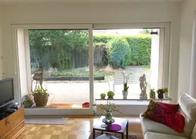 Wohnzimmer mit großer Schiebetür zur Terrasse und Blick in den Garten